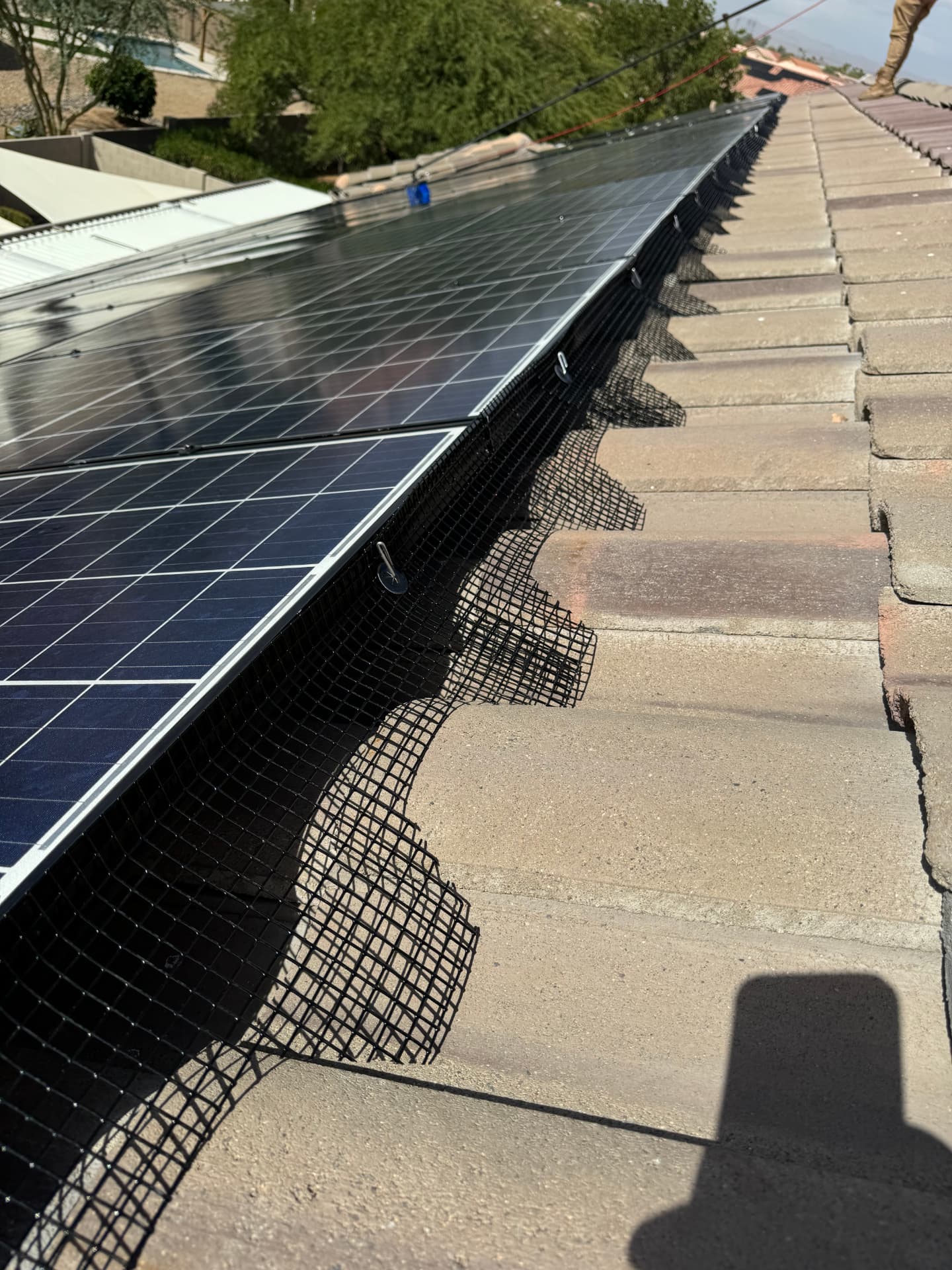 Long run of pigeon mesh installed under a solar array on a tile roof