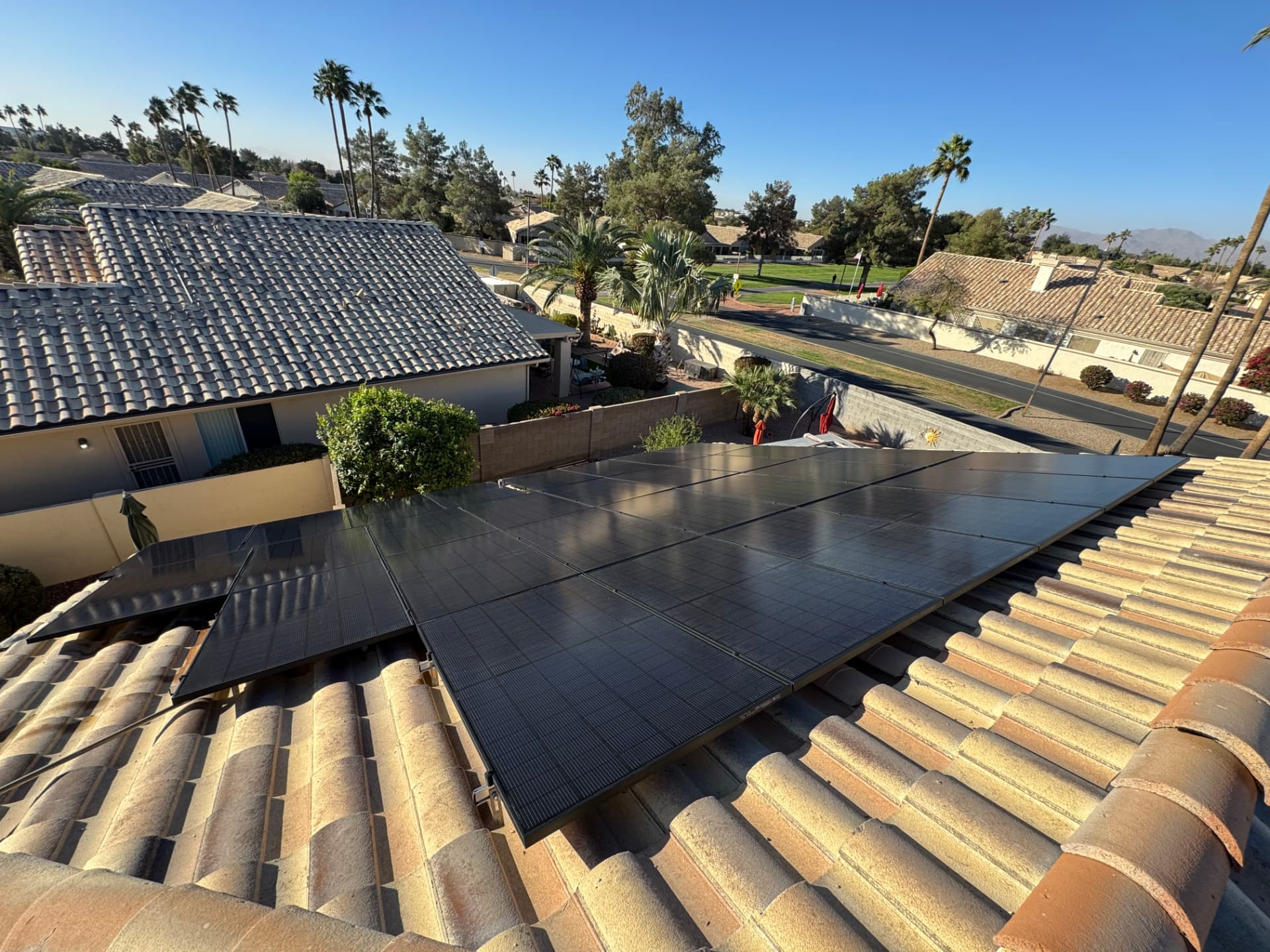 Clean black solar array on a clay tile roof among palm trees